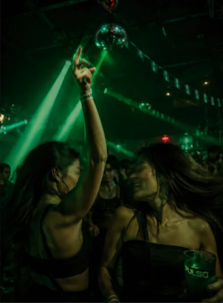 Dos amigas bailando entre láseres verdes