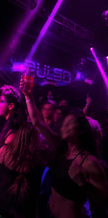 Brindis bajo el cartel de PULSO con luces violetas